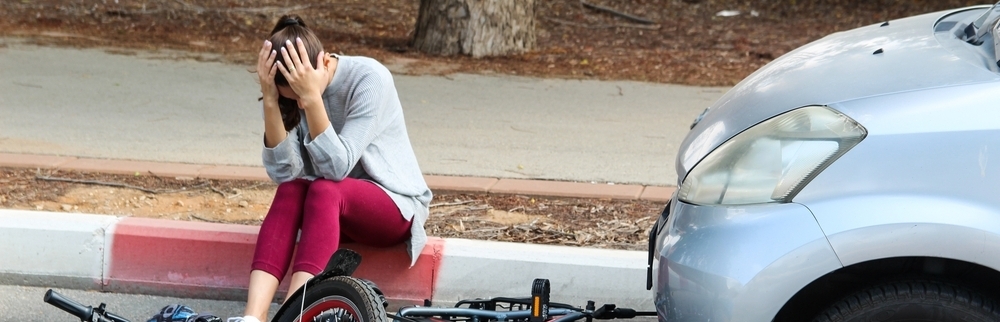 Bicyclist sits on curb after being hit by car